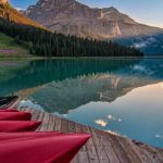 Transforming Landscapes. - Red Canoes on Sea Dock Near Calm Body of Water